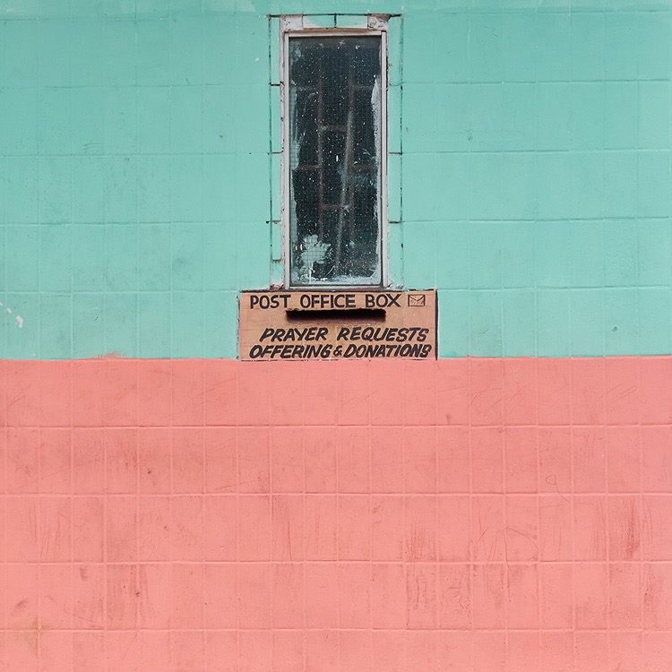 A print of a wall in green and pink showing a post office box sign